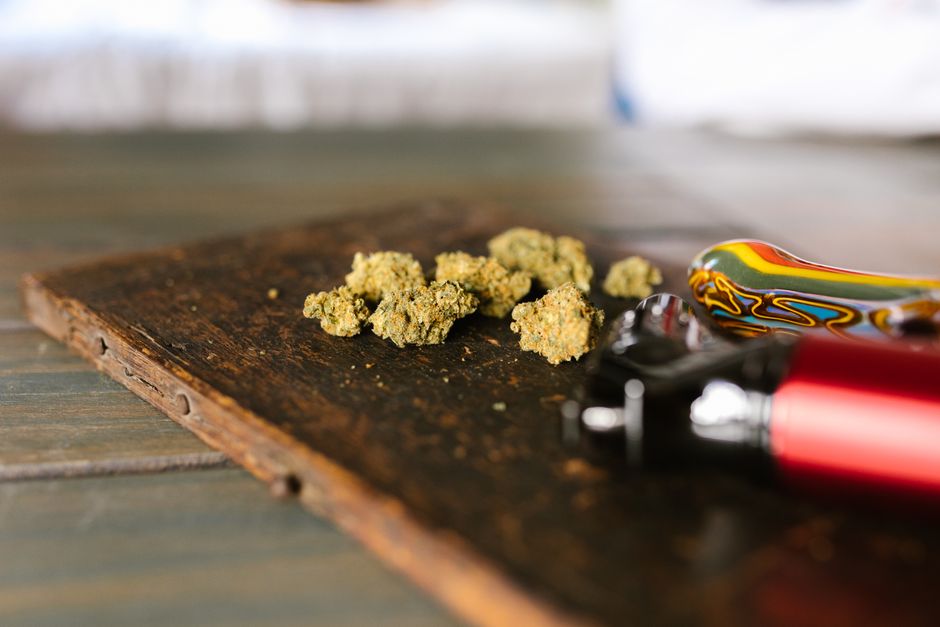 Cogollos de cannabis junto a un vaso de agua sobre una mesilla de noche