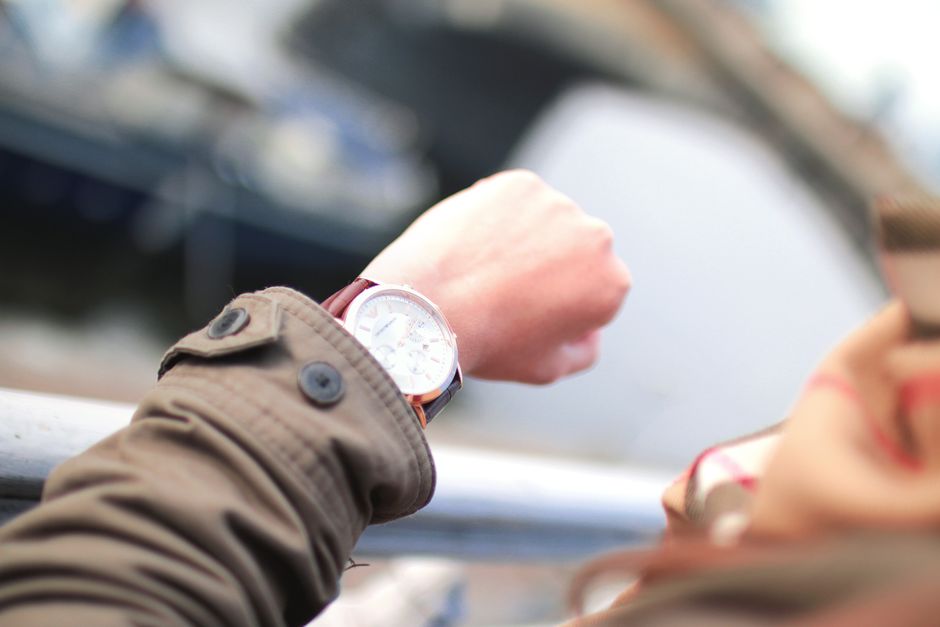 Una persona mirando el reloj mientras espera el efecto de un comestible en el sofá
